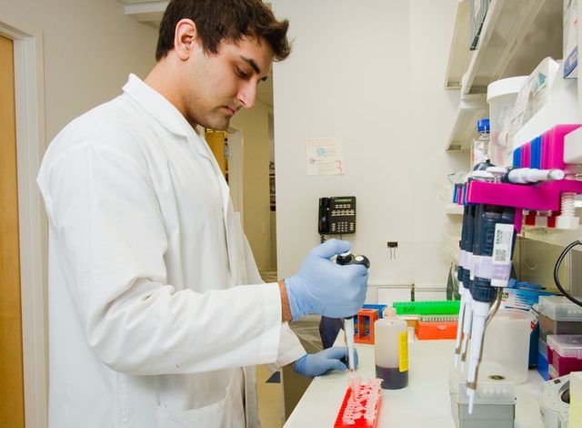 A male scientist in a laboratory pipetting protein reagent into eppendorf tubes